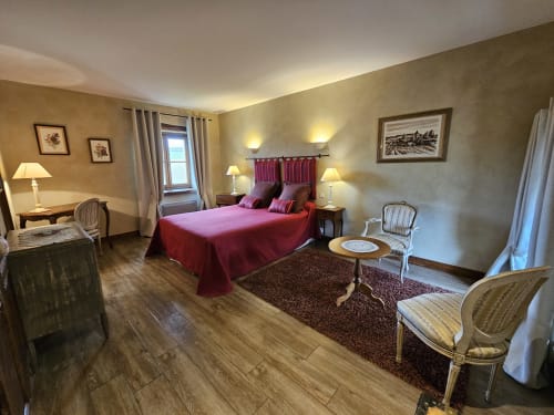 Chambre du Château de Ribourdin avec lit rouge, vue sur le jardin et décoration classique française