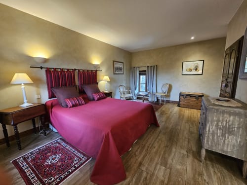 Chambre luxueuse du Château de Ribourdin avec literie rose, rideaux rouges et mobilier d'époque à Chevannes