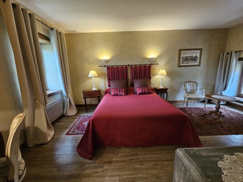 Chambre élégante au Château de Ribourdin avec lit bordeaux, murs crème et vue sur le jardin à Chevannes
