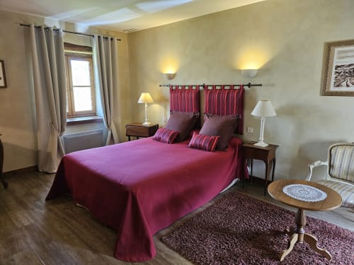 Chambre élégante du Château de Ribourdin avec lit bordeaux, murs jaunes et vue sur le jardin à Chevannes