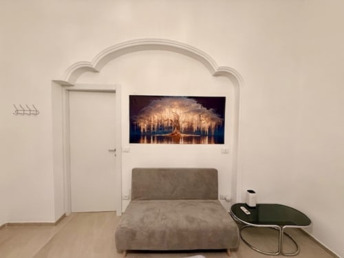 Camera da letto moderna nell'appartamento di Bologna con letto grigio, arcata bianca e quadri con bosco sopra la testata