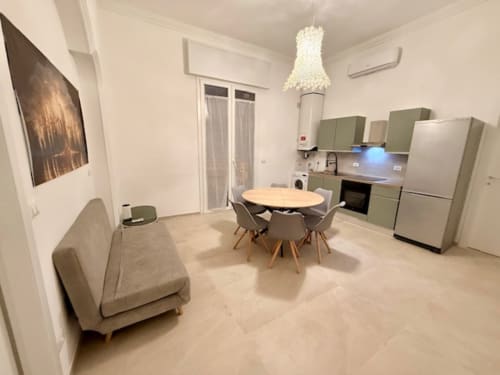 Moderna cucina open-plan e zona pranzo dell'appartamento Effi House Bologna con mobili verde salvia, tavolo rotondo e