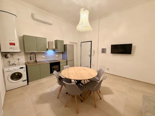 Cucina e zona pranzo moderna di Effi House Bologna con tavolo rotondo in legno, sedie grigie, mobili verdi