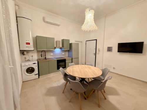 Cucina moderna open-plan e zona pranzo dell'appartamento a Bologna con cabinetry verde, tavolo rotondo e design contemporaneo