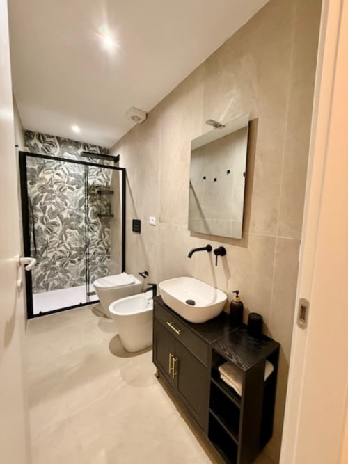 Bagno moderno presso Effi House Bologna con lavabo bianco, mobile nero, water, bidet e doccia walk-in con piastrelle decorate