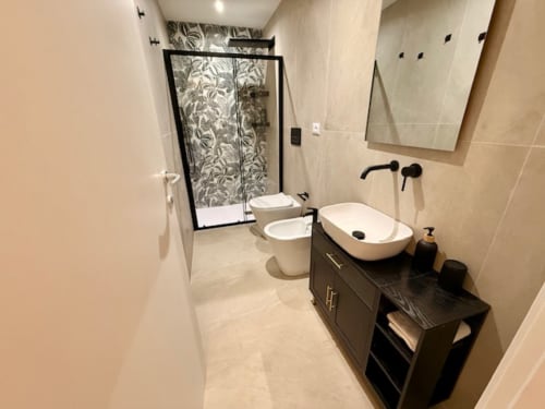 Bagno moderno con vanity nero, lavabo bianco a calice, doccia in vetro con piastrelle decorate e scaldasalviette a Effi House