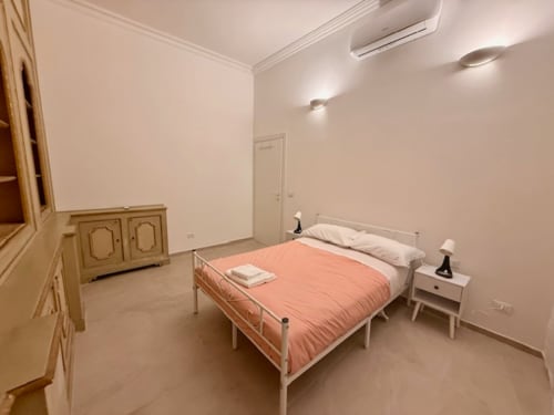Spaziosa camera da letto a Effi House Bologna con letto matrimoniale, comodino bianco, mobili in legno, aria condizionata e vista sulla città