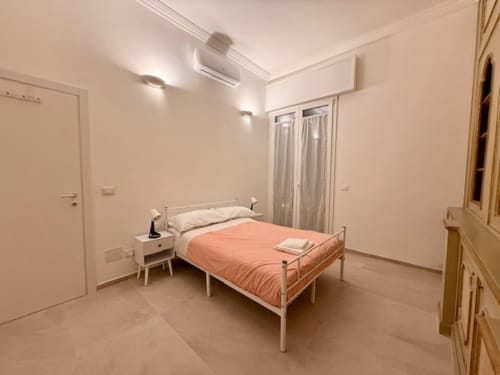 Camera luminosa a Effi House Bologna con letto in metallo, biancheria arancione, comodino bianco e vista sulla città