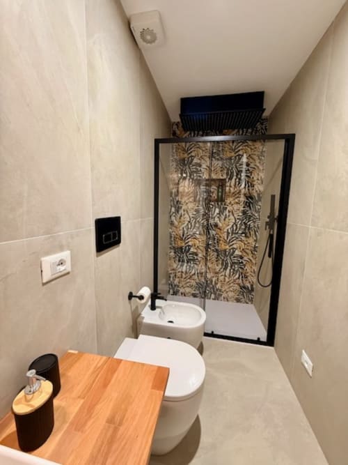 Bagno moderno con toilette bianca, bidet, lavabo e doccia con box a vetri decorati nell'appartamento Effi House Bologna