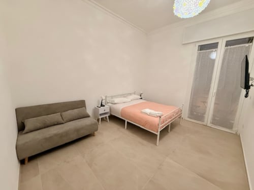 Camera moderna di Effi House Bologna con divano, letto, TV e accesso al balcone con vista sulla città