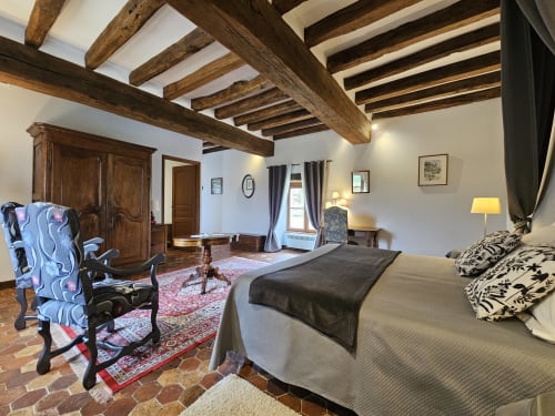 Chambre Château Gaillard au Château de Ribourdin avec poutres apparentes, mobilier d'époque et carrelage en terre cuite