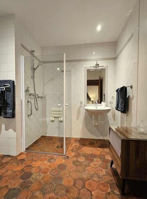 Salle de bains spacieuse et accessible au Château de Ribourdin avec douche à l'italienne, lavabo sur pied, carrelage en terre cuite