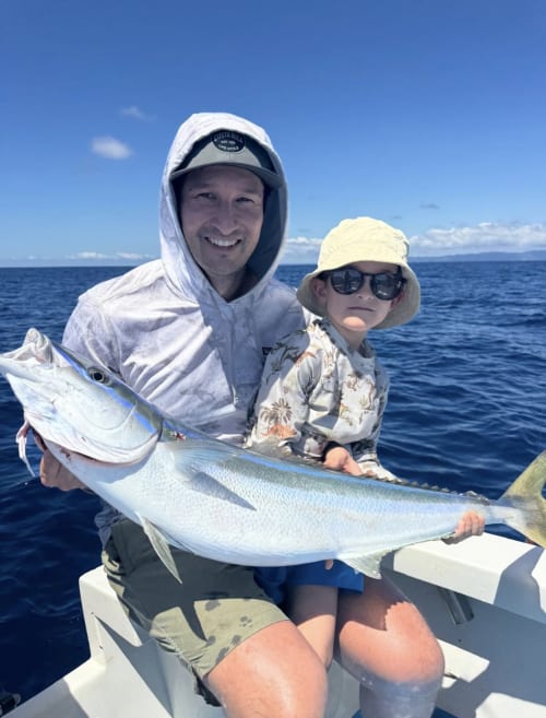 Adult and child hold large fish on boat in Pavones, Costa Rica waters near Hotel Swell Pavones