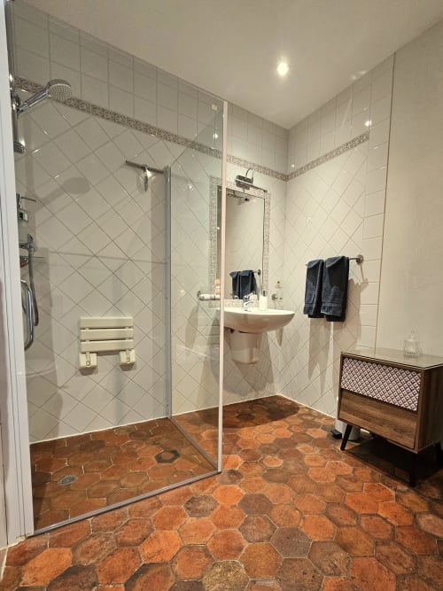 Salle de bain luxueuse au Château de Ribourdin avec douche à l'italienne, carreaux hexagonaux en terre cuite et équipements modernes