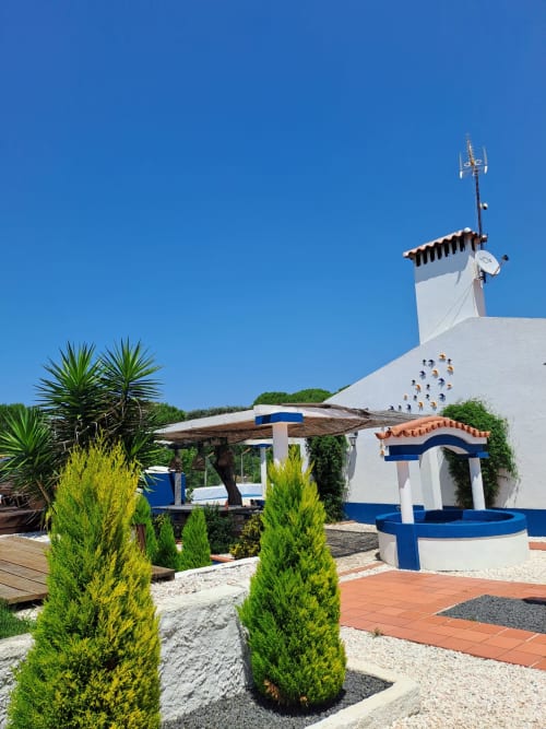 Cottage branco e azul com piscina na Herdade da Cova da Onça em Canha, Portugal, com palmeiras e céu azul cristalino