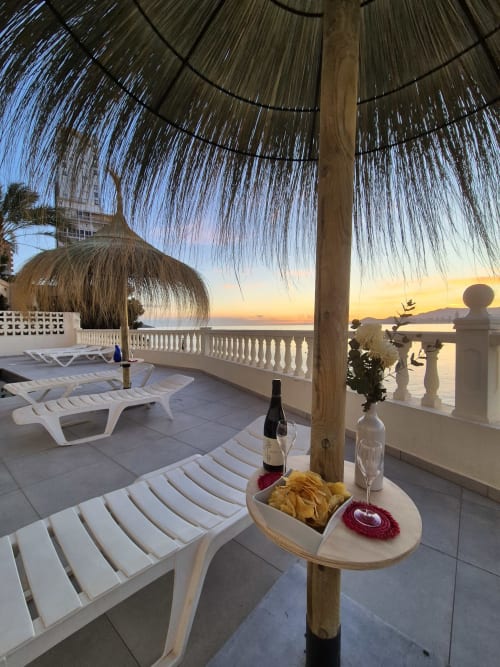 Terraza al atardecer en Portofino Playa con palapas, tumbonas y vista al mar Mediterráneo al anochecer