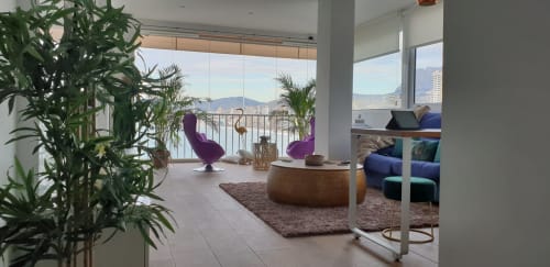 Moderno salón con vistas al mar, sillas moradas, plantas en maceta y balcón con vistas a las montañas en Portofino Playa