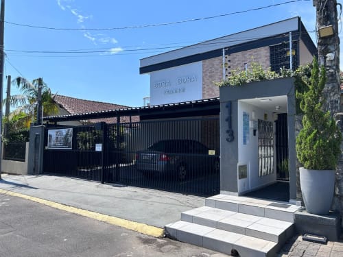 Fachada moderna do edifício Bora Bora Residence em Joinville com portão preto, acabamento branco e vistas para o jardim