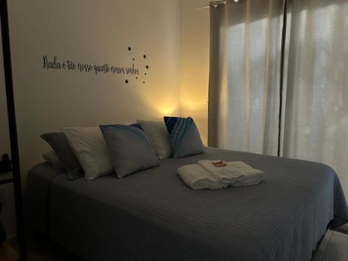 Quarto aconchegante na BORA BORA HOSPEDAGENS em Joinville com cama queen, almofadas e adesivo inspirador na parede