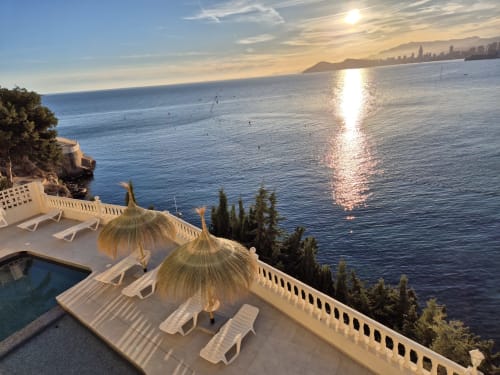 Terraza con vista al mar de Portofino Playa con tumbonas, sombrillas, piscina y atardecer sobre la costa mediterránea