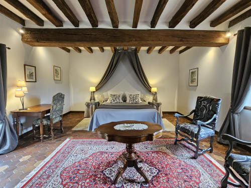 Chambre Château Gaillard au Château de Ribourdin à Chevannes avec poutres apparentes, lit à baldaquin et tapis ornementés