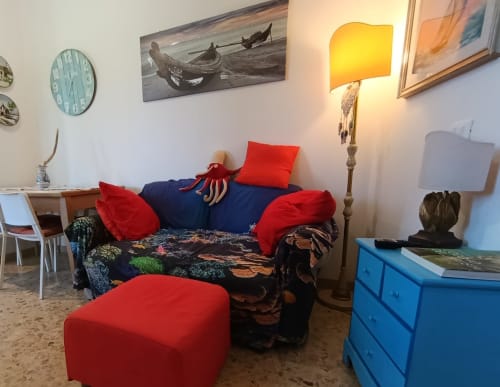 Accogliente salotto di Casa Valentina, appartamento ad Ancona con divano blu navy, cuscini rossi e arredi nautici