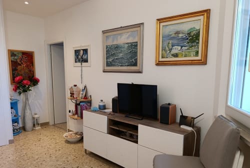 Soggiorno dell'appartamento Casa Valentina ad Ancona con TV, quadri decorativi e balcone con vista sul giardino