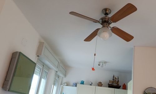 Ventilatore da soffitto con plafoniera nella camera dell'hotel Casa Valentina ad Ancona, pareti bianche e scaffali