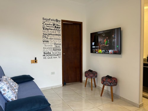 Sala de estar moderna em Joinville com sofá azul, arte na parede, TV de tela plana e bancos decorativos