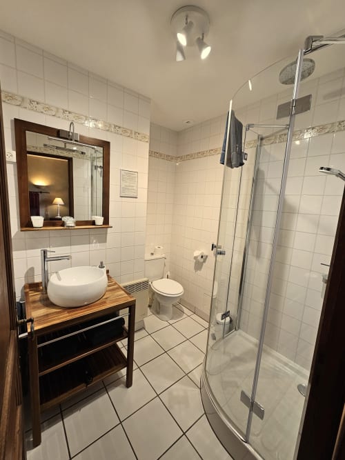Salle de bains moderne avec douche à l'italienne, lavabo rond et meuble de rangement en bois au Château de Ribourdin, Chevannes, France