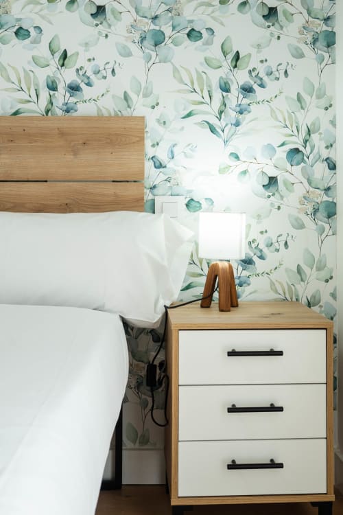 Dormitorio moderno en Los Patios De Feria, Sevilla con mesilla de madera, papel tapiz botánico y ropa de cama blanca