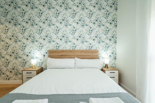 Dormitorio moderno en Los Patios De Feria de Sevilla con papel tapiz floral, cama de madera, ropa de cama blanca y complementos a juego