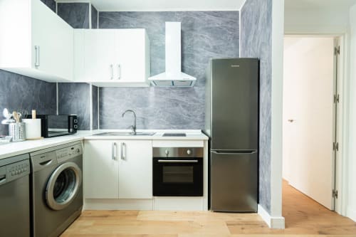 Cocina moderna en apartamento La Orilla de Calatrava, Los Patios De Feria, Sevilla con muebles blancos y acero inoxidable