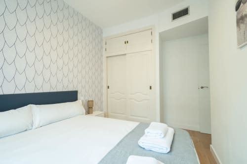 Habitación moderna en Los Patios De Feria, Sevilla con cama queen, papel pintado estampado y puertas blancas