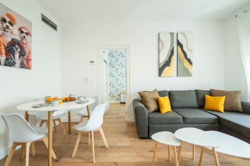 Moderno salón de apartamento en Los Patios De Feria Sevilla con sofá gris, mesa de comedor y detalles en amarillo