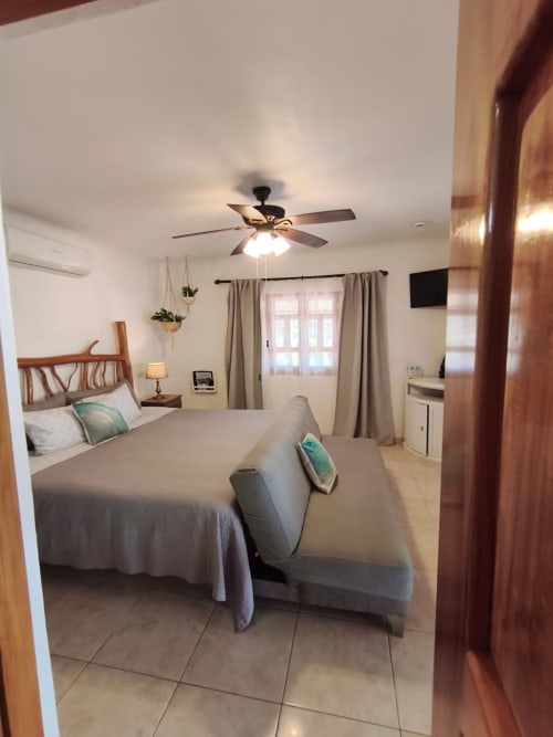 Habitación luminosa en Casa Punta Perula con cama queen, ventilador de techo, TV y puertas con vista al mar en el resort Punta Perula