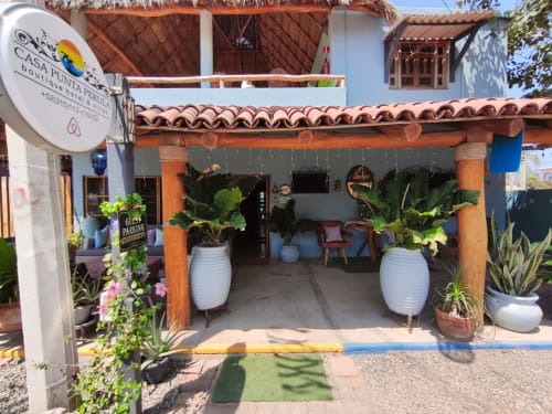 Entrada del Boutique Hotel Casa Punta Perula con señalización colorida, vigas de madera, plantas en macetas y detalles azules