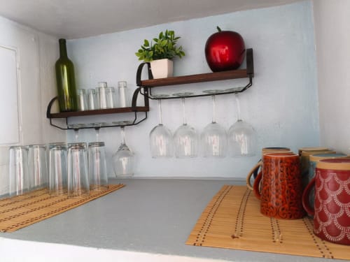Estantes de la cocina de la cabaña Casa Punta Perula con copas de vino, planta en maceta y manzana roja decorativa