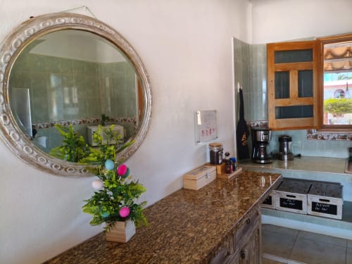 Cocina americana de cabaña frente al mar en Casa Punta Perula con encimera de granito, espejo redondo y ventana con vista al mar