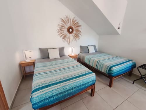 Camas gemelas con ropa de cama de rayas azules en luminosa habitación estudio de Casa Punta Perula, hotel en Punta Perula México con detalles de madera