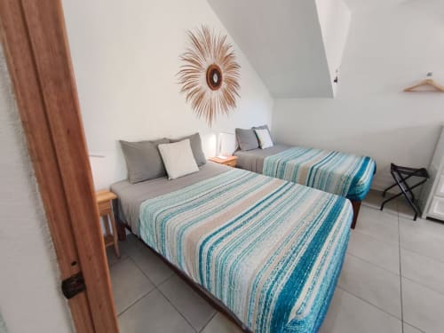 Luminosa habitación con dos camas de ropa rayada, paredes blancas, espejo decorativo y diseño moderno en Casa Punta Perula
