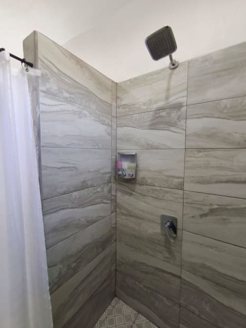 Moderna cabina de ducha con azulejos texturizados en mármol, alcachofa de lluvia y controles digitales en Casa Punta Perula Boutique Hotel