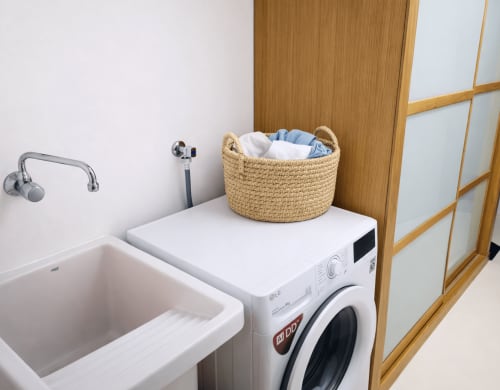 Zona de lavandería en el apartamento Lisiña de Holibai, Baiona con lavadora y cesta tejida