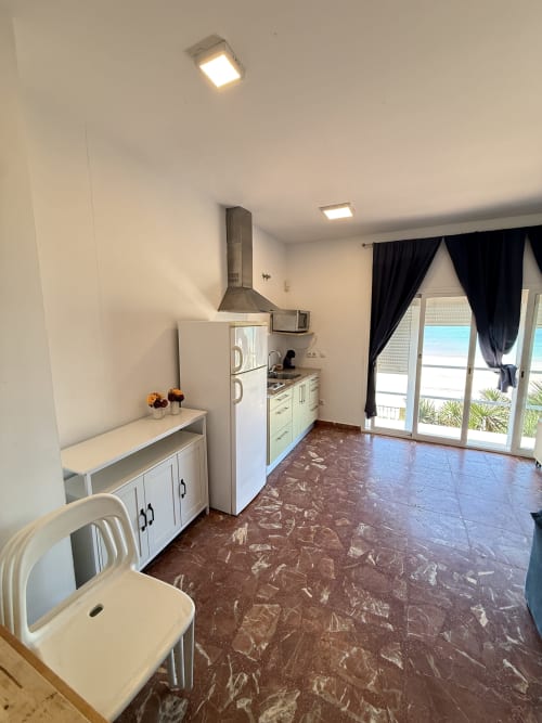 Cocina moderna en apartamento frente al mar, Matalascañas, con muebles blancos, campana de acero inoxidable, refrigerador y vista al mar