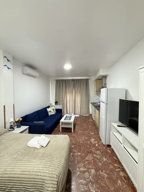 Moderno apartamento estudio en Apartamentos A la Orilla del Mar con cama doble, sofá azul, cocina americana y vistas al mar