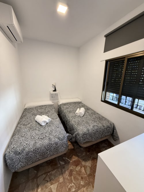 Dos camas gemelas con colchas estampadas y toallas enrolladas en una habitación luminosa de Apartamentos A la Orilla del Mar, Matalascañas