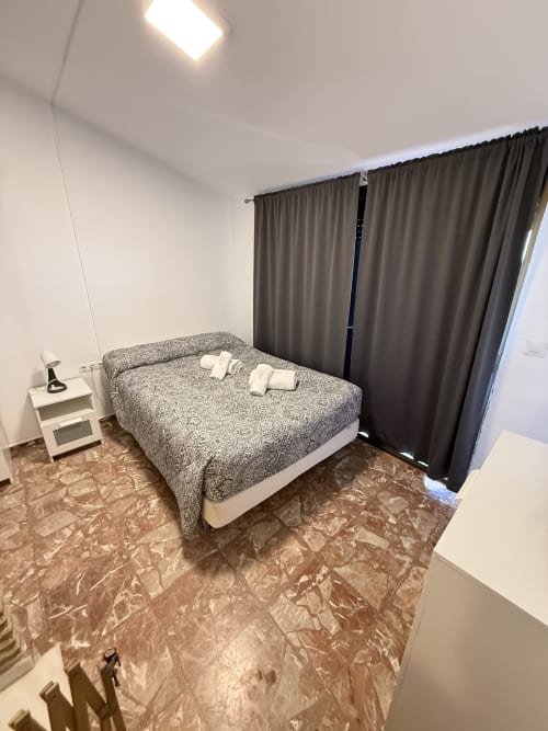 Dormitorio en Apartamentos A la Orilla del Mar, Matalascañas con cama matrimonial, cortinas oscuras y piso de mármol