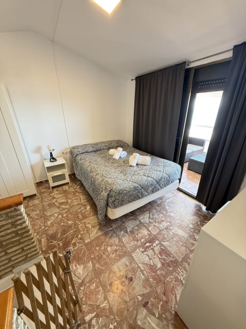 Dormitorio en Apartamentos A la Orilla del Mar, Matalascañas con cama, mesita de noche, cortinas oscuras, puerta de terraza y mármol