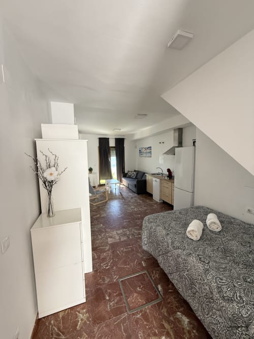 Apartamento estudio en Matalascañas con vistas al mar, cama con pantuflas, cocina americana, sofá y mobiliario moderno