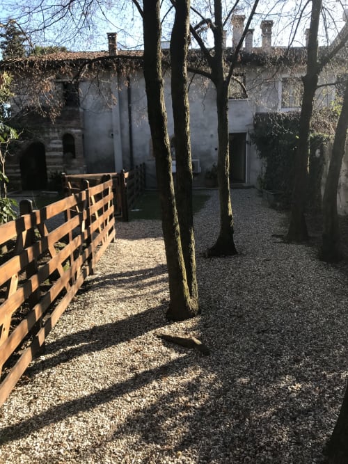 Corte Roveggia garden courtyard with wooden gate, bare trees, and historic Italian stone building in Verona